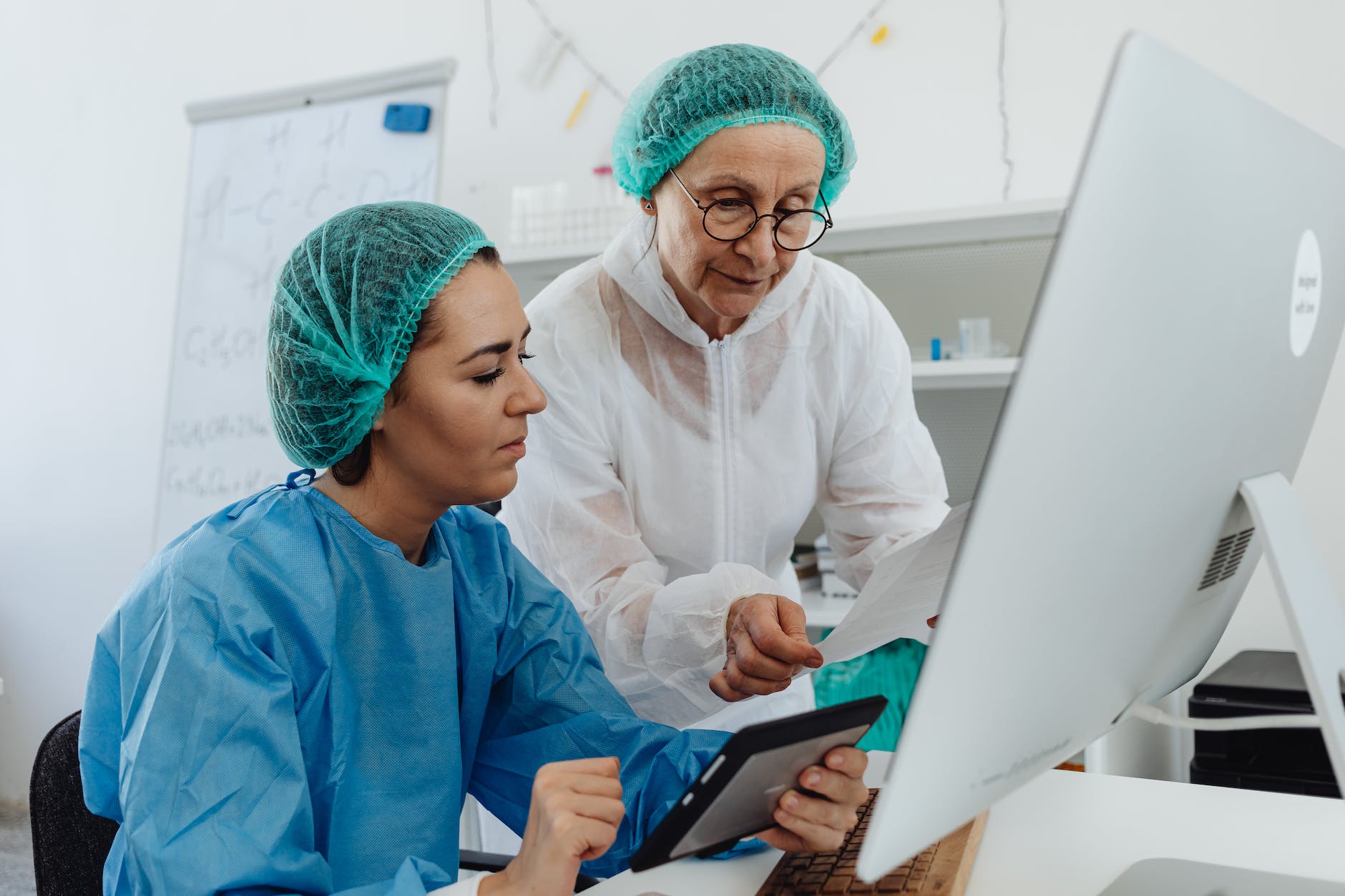 researchers wearing hair nets and coveralls reading a report